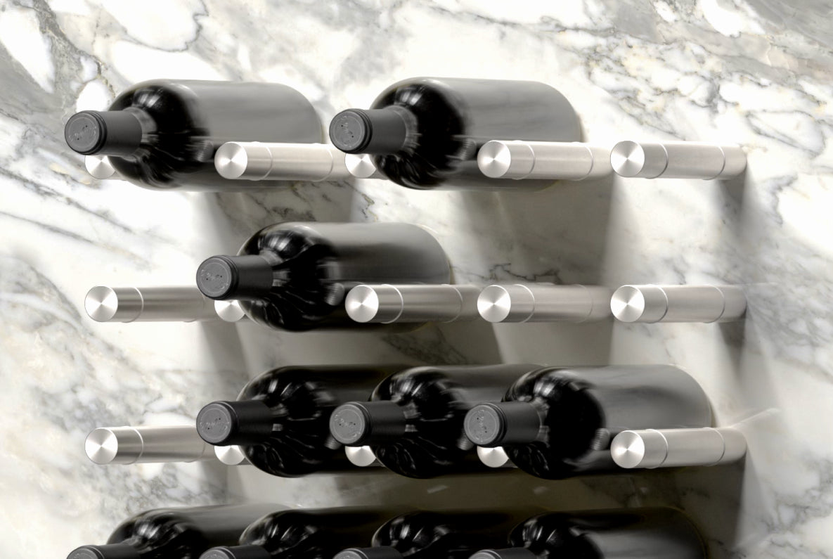 Partially filled wall-mounted metal wine pegs holding seven bottles on a marble wall